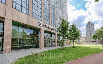 Kantoorpand aan Prins Bernhardplein 200 in Amsterdam Amstel, met moderne gevel en grootse ramen. Ideale locatie voor kantoorruimte huren in het Amstelgebouw. Gelegen in een groene omgeving.
