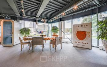 Licht kantoor op Prins Bernhardplein 200 in Amsterdam Amstel met vergadertafel omringd door stoelen en uitzicht op de stad. Geschikt voor kantoorruimte huren.