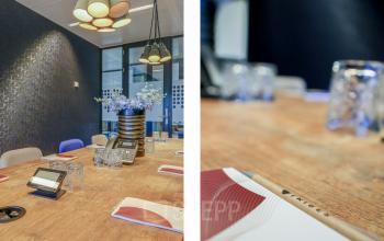 Stijlvolle vergaderruimte met houten tafel, moderne verlichting en decoratieve bloemen op een kantoorpand in Amsterdam Amstel.