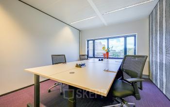 Zakelijke kantoorruimte te huur op Prins Bernhardplein 200 in Amsterdam Amstel met vergadertafel, stoelen en uitzicht op de stad.