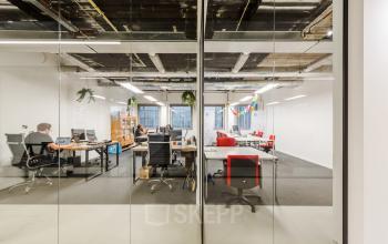 Moderne kantoorruimte aan de Wibautstraat 135 in Amsterdam Amstel, met strakke werkplekken en vergaderruimtes zichtbaar door glazen wanden.