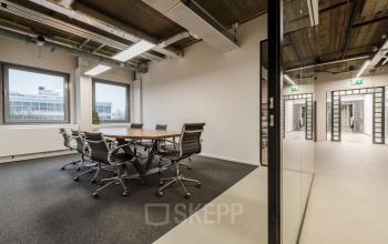 Moderne vergaderruimte binnen kantoorpand aan Wibautstraat 135, Amsterdam Amstel met grote tafel en comfortabele stoelen