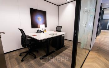 Moderne kantoorruimte op Amstelplein 8, Amsterdam Amstel, met een strak bureau en comfortabele stoelen. Ideaal voor wie een kantoorruimte wil huren. Glazen wanden zorgen voor een open en lichte sfeer.