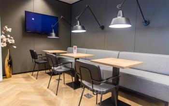 Moderne kantoorruimte met houten vloer en stijlvolle verlichting op Amstelplein 8, Amsterdam Amstel. De ruimte beschikt over tafels en stoelen, perfect voor huur als werkplek of vergaderruimte.