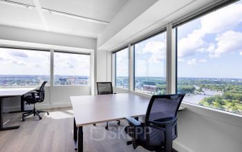 Lichte kantoorruimte met grote ramen en uitzicht op de Amstel, met bureaus en stoelen op Amstelplein 8, Amsterdam Amstel. Geschikt voor kantoorruimte huren.