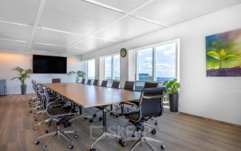Moderne vergaderruimte in kantoorpand op Amstelplein 8, Amsterdam Amstel, met grote tafel en verstelbare stoelen bij ruime ramen. Ideaal voor kantoorruimte huren.