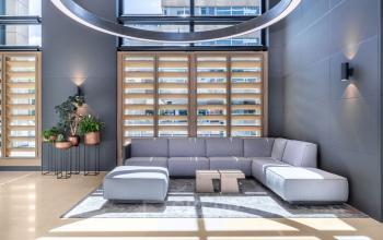Moderne kantoorruimte huren aan Amstelplein 8 in Amsterdam Amstel met een strakke, lichte inrichting voorzien van comfortabele grijze banken en houten accenten, perfect voor zakelijke gesprekken of informele bijeenkomsten.