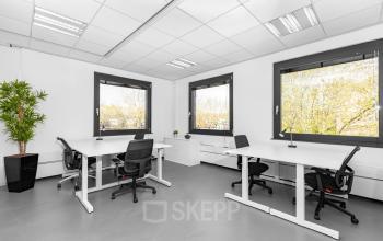 Lichte en moderne kantoorruimte in kantoorpand aan De Cuserstraat 93, Amsterdam Buitenveldert, met strakke bureaus en groene planten bij de ramen.