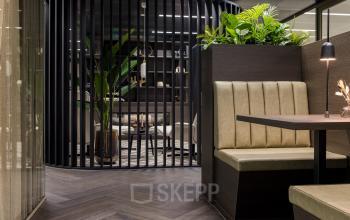 Stijlvolle kantoorruimte binnen het kantoorpand op Walborg 2A, Amsterdam Buitenveldert, met moderne inrichting en planten. Ruime werkplekken met strakke lijnen en warme kleuren voor professioneel gebruik.