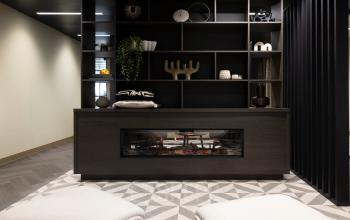 Gezellige kantoorruimte met een moderne open haard, stijlvolle planken met decoraties en een comfortabele zithoek. Ideaal voor wie een inspirerend kantoorpand wil huren in Amsterdam Buitenveldert.