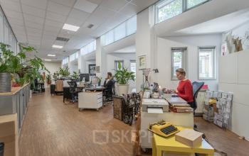 Moderne kantoorruimte op Oudeschans 21 in Amsterdam Centrum met werkende personen en comfortabele werkplekken.