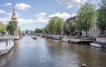 Uitzicht op de gracht voor het kantoorpand gelegen aan Oudeschans 21 in Amsterdam Centrum met diverse boten en historische gebouwen.