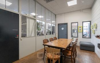 Vergaderruimte met houten tafel en comfortabele zitgelegenheid in een licht kantoorpand op Oudeschans 21, Amsterdam Centrum.