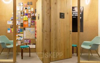 Modern ingerichte kantoorruimte met houten cabine en comfortabele stoelen in kantoorpand aan Vijzelstraat 68-78, Amsterdam Centrum.