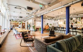 Moderne en ruime kantoorruimte op Nieuwezijds Voorburgwal 162, Amsterdam Centrum, met lounge en werkplekken, grote ramen, houten vloeren en strakke inrichting. Geschikt voor vergaderen en werken.