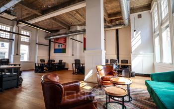 Kantoorpand op Nieuwezijds Voorburgwal 162 in Amsterdam Centrum met een stijlvolle open werkruimte, voorzien van houten vloeren en leren stoelen, ideaal voor kantoorruimte huren.