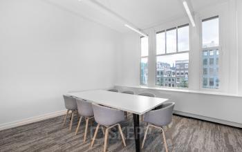 Lichte kantoorruimte huren op het Rokin 92-96 in Amsterdam Centrum, met grote ramen en moderne stoelen rond een lange tafel, ideaal voor vergaderingen.