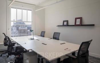 Kantoorruimte huren aan het Rokin 92-96, Amsterdam Centrum. Moderne en functionele werkruimte met grote ramen voor natuurlijke lichtinval, voorzien van kantoormeubilair en vergadertafel, ideaal voor zakelijke activiteiten.