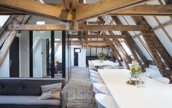 Moderne kantoorruimte op de bovenste verdieping van Rokin 92-96, Amsterdam Centrum, met houten balken, lange tafels en comfortabele zitgedeeltes. Ideaal voor vergaderingen of teamwerk. Perfecte locatie om kantoorruimte te huren.