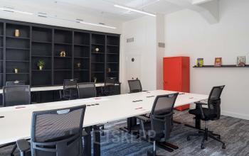 Kantoorruimte huren aan Rokin 92-96 in Amsterdam Centrum met moderne werkplekken, ergonomische bureaustoelen, witte tafels en een opvallende rode kast, omgeven door strakke, donkere boekenkasten.