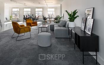 Interieur van een modern kantoor op Leidsestraat 32, Amsterdam Centrum. Gezellige zithoek met stijlvolle meubels en meerdere werkplekken beschikbaar voor kantoorruimte huren.