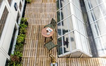 Buitenruimte van kantoorpand op Muiderstraat 1, Amsterdam Centrum, met houten terras, tafels en planten. Geschikt als ontspanningsplek bij een kantoorruimte huren.