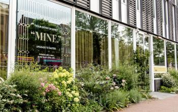 Entree van het kantoorpand op Muiderstraat 1, Amsterdam Centrum, met gevelplanten en grote ramen. Ideaal voor wie kantoorruimte wil huren in een levendige omgeving.