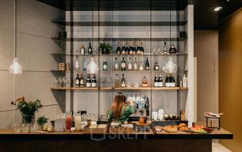 Moderne kantoorruimte in Amsterdam Centrum met een goed gevulde bar en een persoon die koffie maakt. Uitermate geschikt als ontspanningsruimte binnen het kantoorpand.