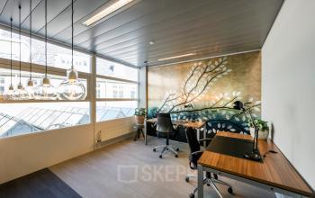 Kantoorruimte huren op Muiderstraat 1 in Amsterdam Centrum met modern ingerichte werkplekken, veel natuurlijk licht en elegante wanddecoratie.