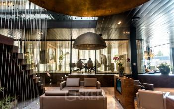 Luxe kantoorpand aan de Muiderstraat 1 in Amsterdam Centrum, met moderne inrichting en elegante zitruimte. Personen zijn druk in overleg in een vergaderkamer. Ideaal voor bedrijven die kantoorruimte willen huren.