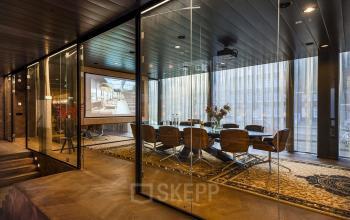 Vergaderruimte met glazen wanden op Muiderstraat 1 in Amsterdam Centrum, met lange tafel en stoelen, geschikt voor zakelijke bijeenkomsten. Ideaal kantoor voor wie kantoorruimte wil huren.