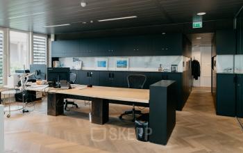 Moderne kantoorruimte op Muiderstraat 1 in Amsterdam Centrum met ruime werkplek, donkere opbergruimtes en een groot houten bureau. Ideaal voor bedrijven die een stijlvolle plek willen huren in hartje Amsterdam.