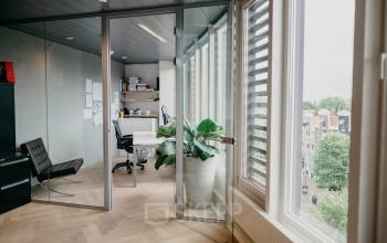 Kantoorpand op Muiderstraat 1, Amsterdam Centrum, met glazen wanden, houten vloer en uitzicht op de stad, geschikt voor kantoorruimte huren.