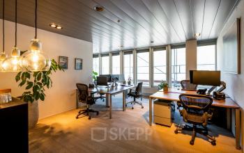 Gezellig ingerichte kantoorruimte met bureaus en moderne stoelen in het kantoorpand op Muiderstraat 1, Amsterdam Centrum; perfect voor een productieve werkdag.