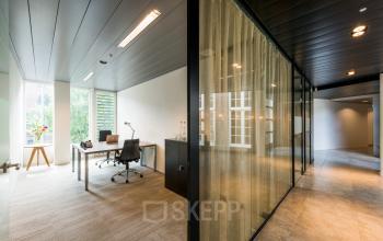 Lichte kantoorruimte met moderne inrichting op Muiderstraat 1, Amsterdam Centrum. Kantoor met houten bureau, comfortabele stoel en grote ramen voor natuurlijk licht. Elegant en klaar voor gebruik.