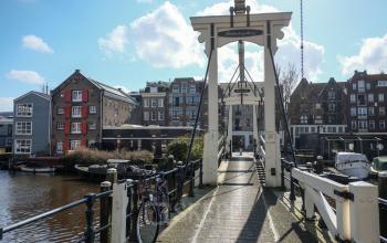 Gezicht op Prinseneiland 23A in Amsterdam Centrum, met een charmante ophaalbrug en historische panden langs het water, ideaal voor kantoorruimte huren.