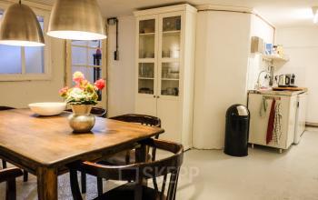 Gezellige kantoorruimte met houten tafel, stoelen en een keukentje op Prinseneiland 23A, Amsterdam Centrum. Ideaal voor kantoorruimte huren met een huiselijke sfeer.