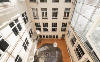 Binnenplaats van het kantoorpand aan Prins Hendrikkade 21 in Amsterdam Centrum, met veel ramen en een glazen overkapping.