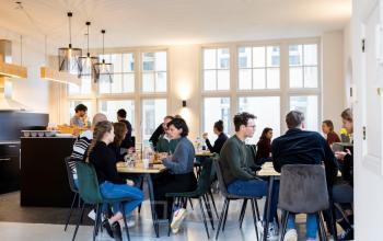 De gezellige ruimte op Prins Hendrikkade 21 in Amsterdam Centrum toont mensen die in een lichte en moderne kantoorruimte ontspannen en samenwerken. Ideaal voor wie kantoorruimte wil huren in een creatieve omgeving.