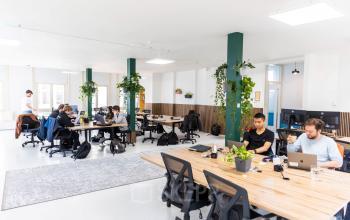 Moderne kantoorruimte op Prins Hendrikkade 21, Amsterdam Centrum met open werkplekken en werknemers die bezig zijn met laptops en notities, geschikt voor bedrijven die kantoorruimte willen huren.