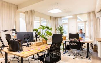 Moderne kantoorruimte huren aan de Prins Hendrikkade 21 in Amsterdam Centrum, met werkplekken, bureaus, planten en een werkende persoon. Sfeervol en professioneel ingericht voor dagelijks kantoorwerk.