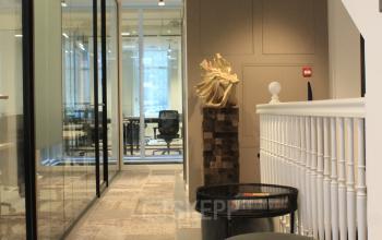 Binnenkant van kantoorpand op Hekelveld 8-10 in Amsterdam Centrum, met moderne inrichting en werkplekken achter glazen wanden. Stoelen en decoraties accentueren de ruimte.