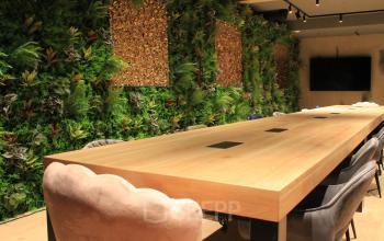 Ruime vergaderruimte met een lange houten tafel, omringd door groene plantenwand in het kantoorpand op Hekelveld 8-10, ideaal voor kantoorruimte huren in Amsterdam Centrum.
