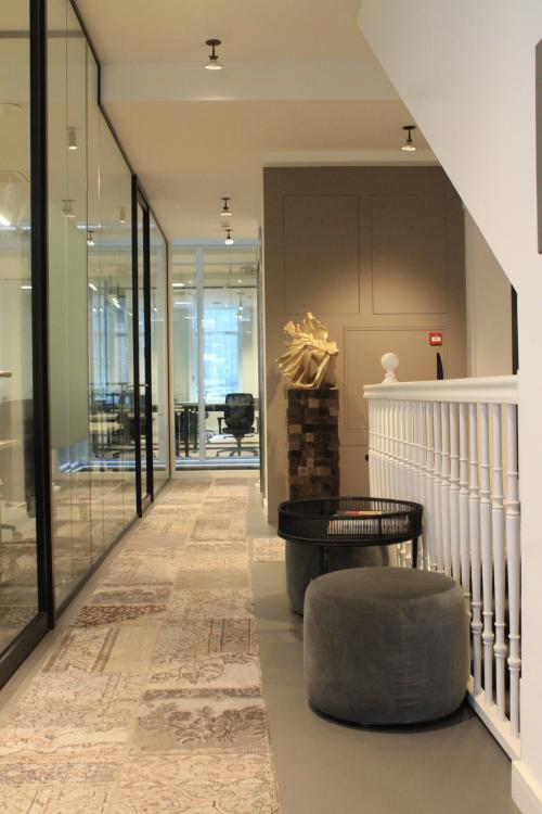 Binnenkant van kantoorpand op Hekelveld 8-10 in Amsterdam Centrum, met moderne inrichting en werkplekken achter glazen wanden. Stoelen en decoraties accentueren de ruimte.