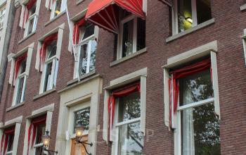 De buitenkant van een kantoorpand op Singel 126 in Amsterdam Centrum met rood-witte zonneschermen, ideaal voor kantoorruimte huren.