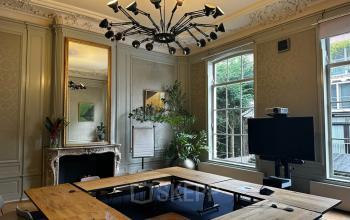 Historische kantoorruimte op Singel 126, Amsterdam Centrum, met elegante wandpanelen, een grote houten vergadertafel, moderne verlichting, een open haard en grote ramen die veel natuurlijk licht binnenlaten.