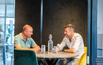 Twee mannen overleggen in een moderne, gemeubileerde kantoorruimte aan de Singel 126 in Amsterdam Centrum, ideaal voor wie een kantoor wil huren.