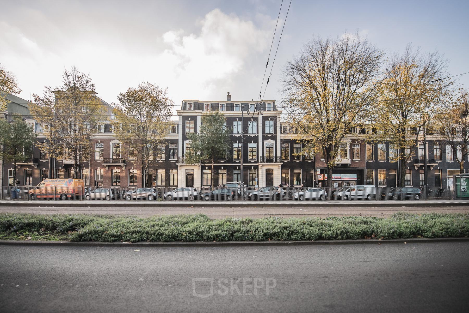 Exterieur van het kantoorpand op Westeinde 14-16, Amsterdam Centrum met geparkeerde auto's en bomen langs de straat.
