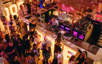 Drukke bedrijfsevenementen in een kantoortuin met bar op Weesperplein 4b, Amsterdam Centrum, met mensen die netwerken tijdens een borrel.