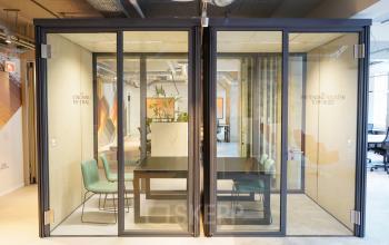Moderne kantoorruimte huren met twee glazen vergadercabines op Weesperplein 4b in Amsterdam Centrum, ideaal voor zakelijke gesprekken en geconcentreerd werken.